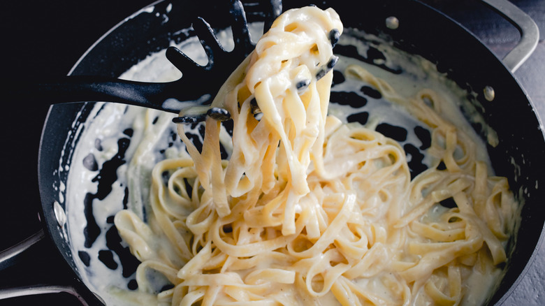 Scooping fettuccine in alfredo sauce