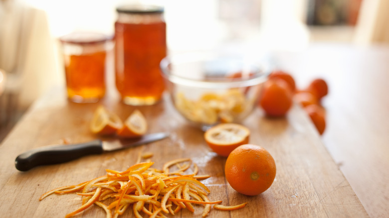 Oranges with strips of peel with marmalade in background