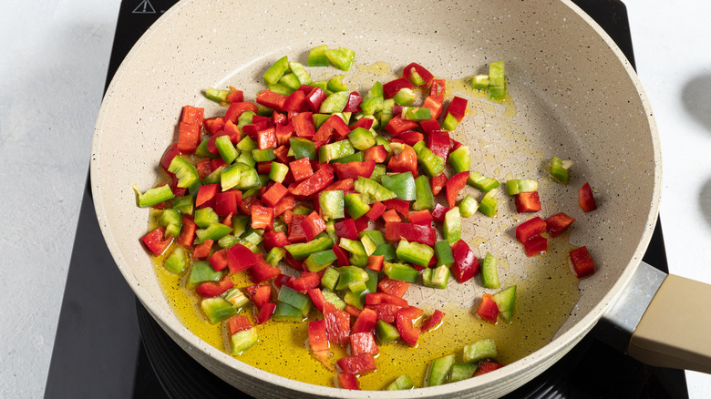 Skillet with red and green bell peppers in it