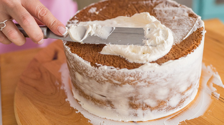 Pastry decorator putting frosting on a cake