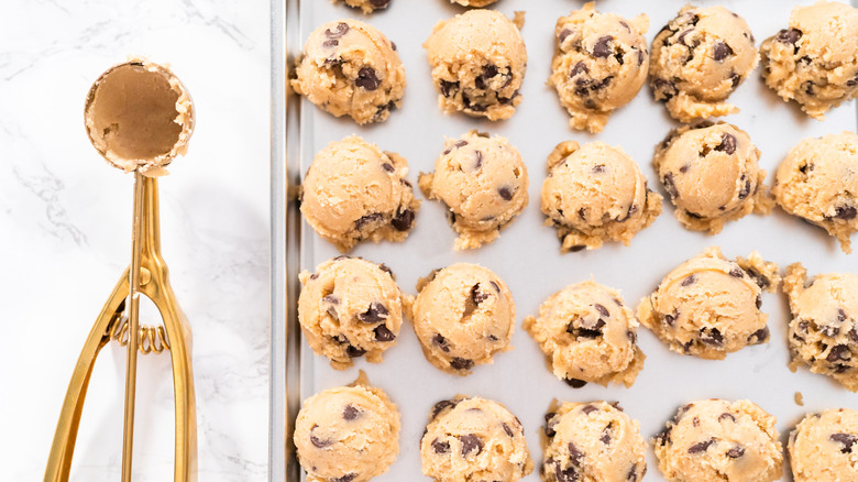 small scoop with cookie dough balls on baking sheet