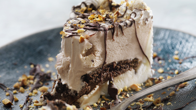 A slice of cookie dough ice cream cake with chocolate sauce