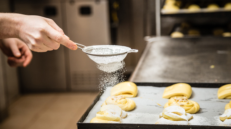 baker decorating with powdered sugar