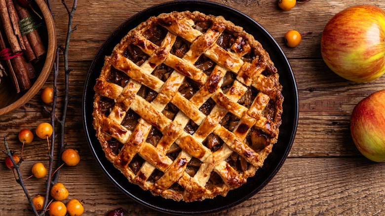 Whole apple pie with lattice crust on a black dish