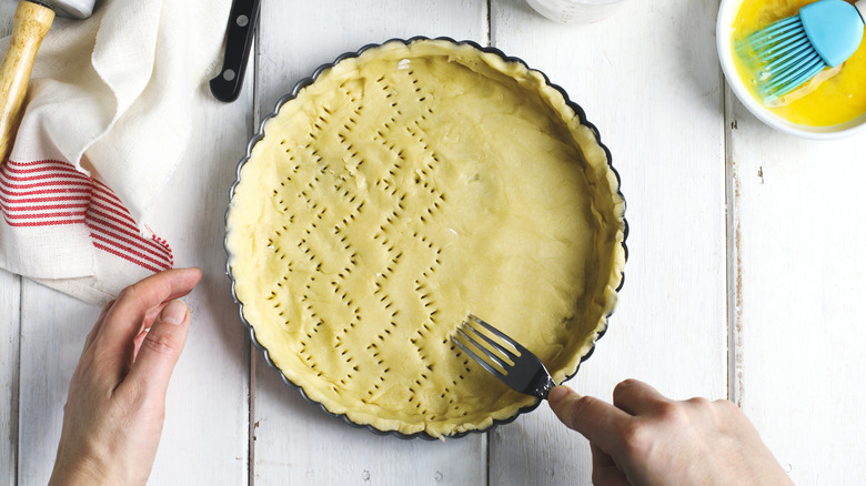 pie crust on counter with ingredients and ornate fork design