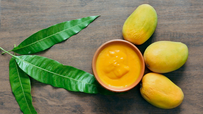 Bowl of kesar mango pulp and whole mangoes