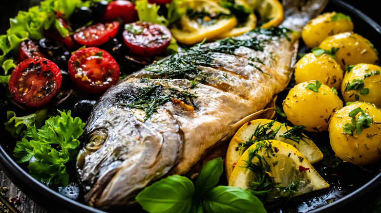 Whole roasted fish with herbs, lemons, and tomatoes