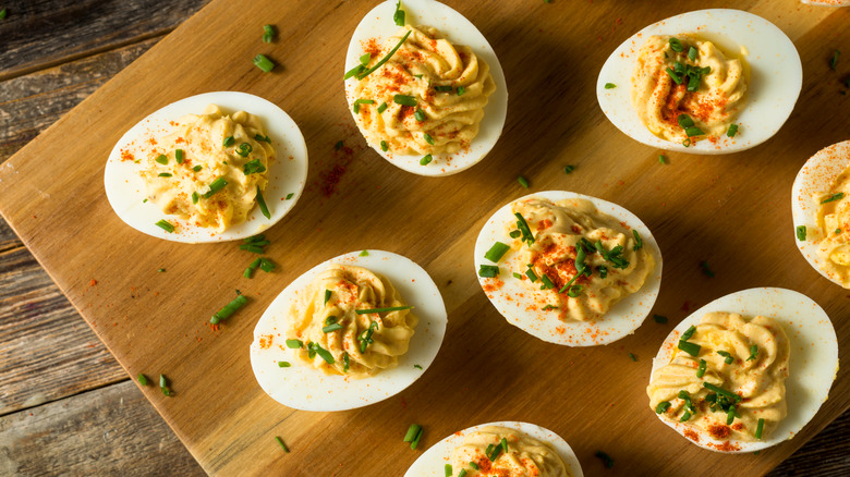 Deviled eggs with chives and paprika on a wooden board