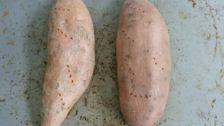 pierced sweet potatoes on sheet