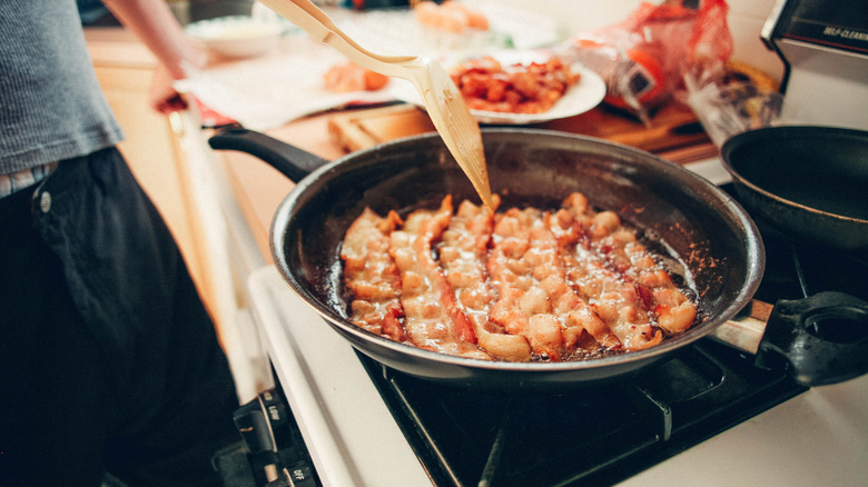 Person cooking bacon in a pan