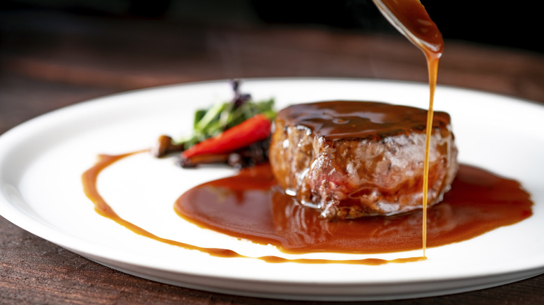 Glossy sauce being spooned over cooked steak