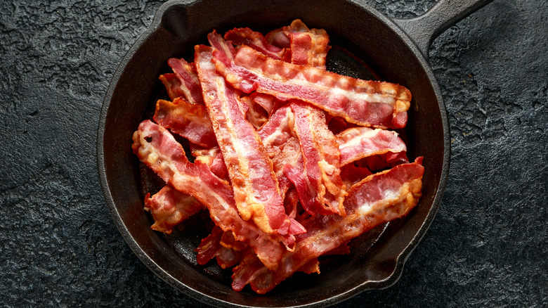 Spiced cooked bacon strips on cutting board