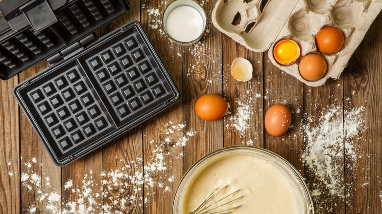 waffle iron with batter and ingredients on table