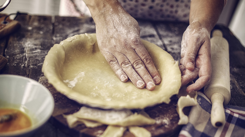 hands forming pie crust into pie plate