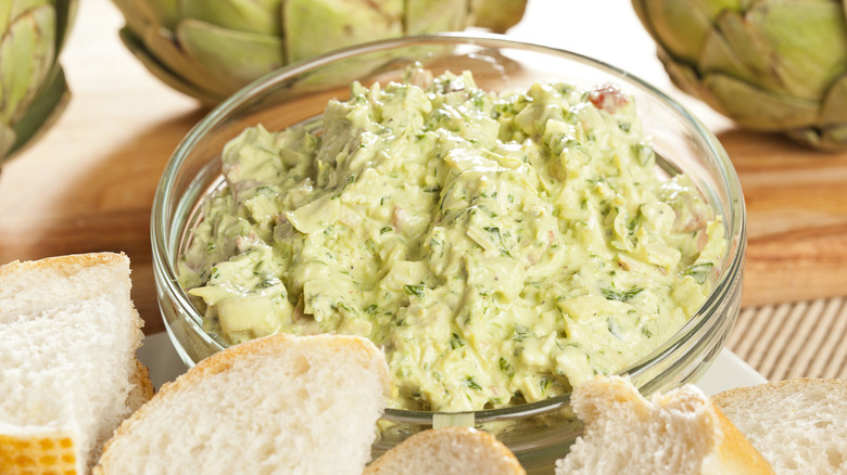 a bowl of artichoke dip alongside some bread