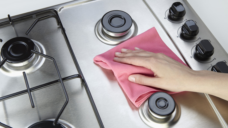 cleaning a steel stovetop with a pink rag