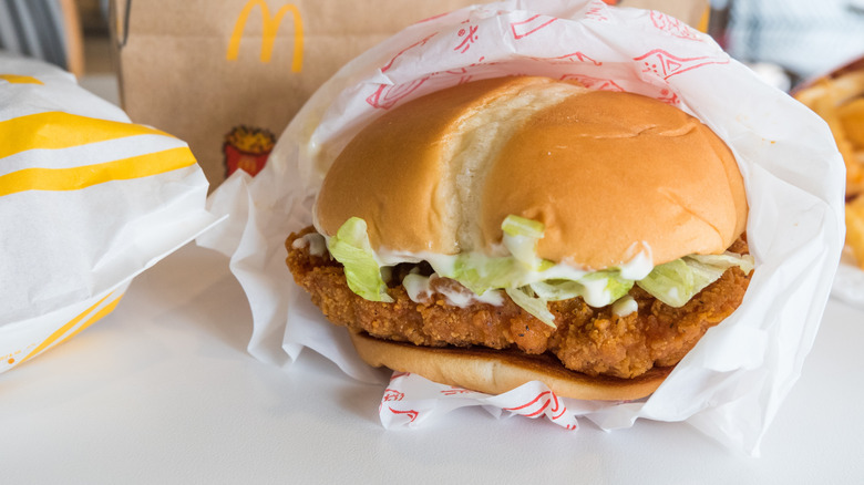 A McDonald's chicken sandwich topped with lettuce and mayo sits unwrapped on a table