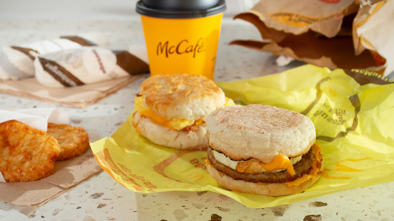 Two McDonald's breakfast sandwiches, coffee, and hashbrowns on table