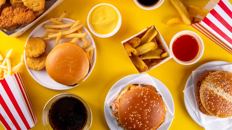 assortment of burgers, fries, dipping sauces, and fast food items on yellow background