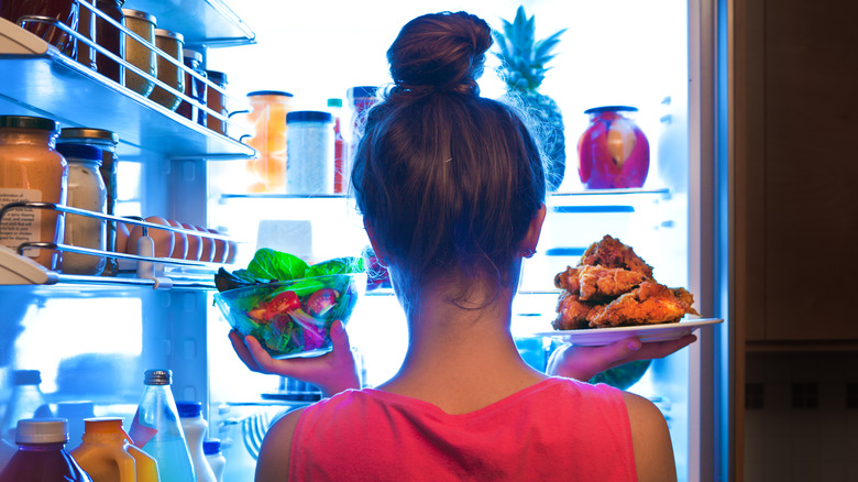 woman putting uncovered food in refrigerator