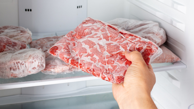 person pulling frozen meat from freezer