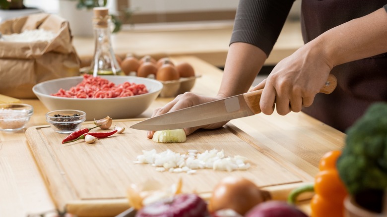 woman dicing onions on chopping board