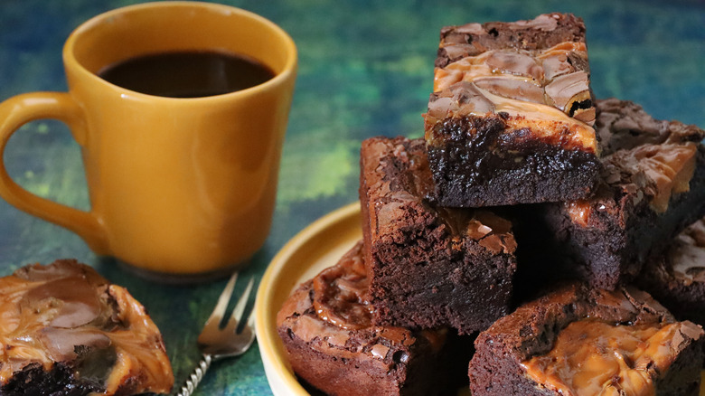 a batch of brownies next to a cup of coffee