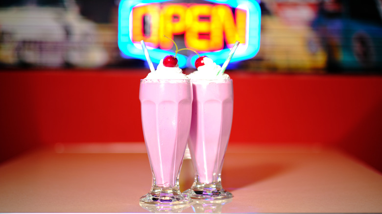 Vintage style strawberry milkshakes in front of a neon sign