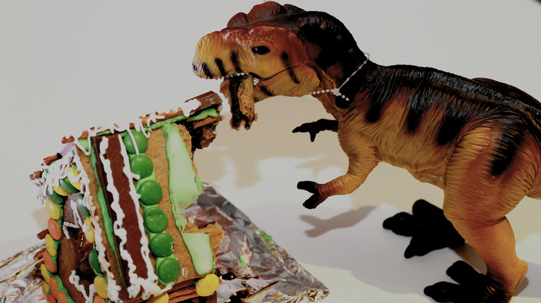 Toy dinosaur eating gingerbread house