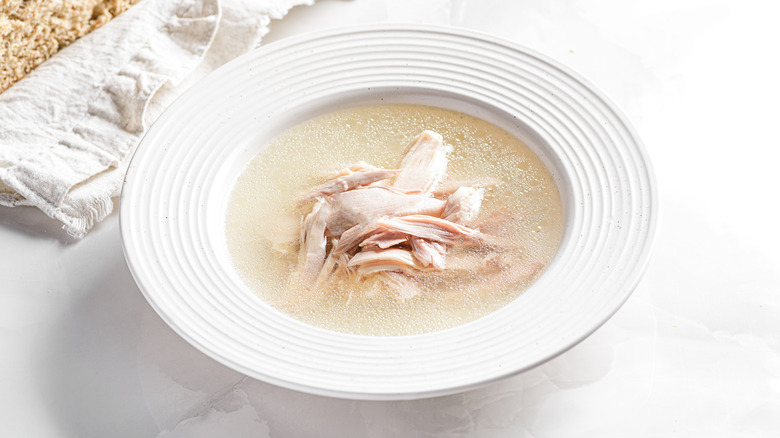 Pale chicken broth in bowl with chicken breast meat