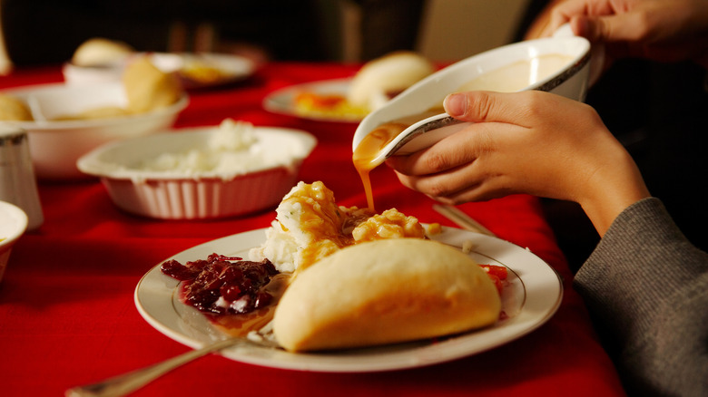 pouring gravy on plate of food