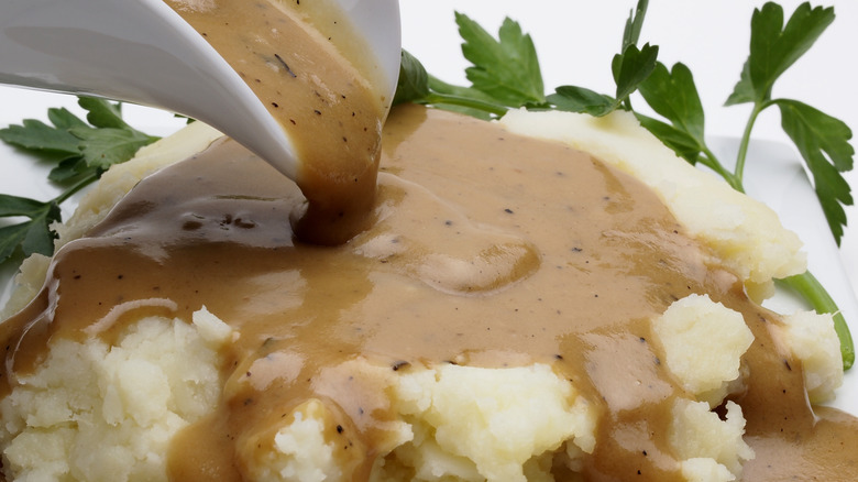 pouring gravy on mashed potatoes