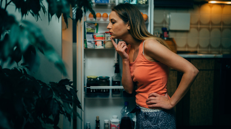 woman looking into open fridge