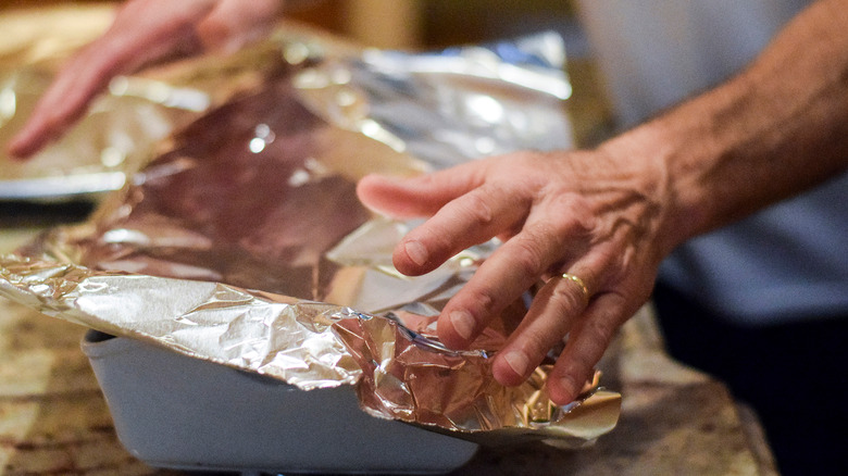 someone placing foil over dish