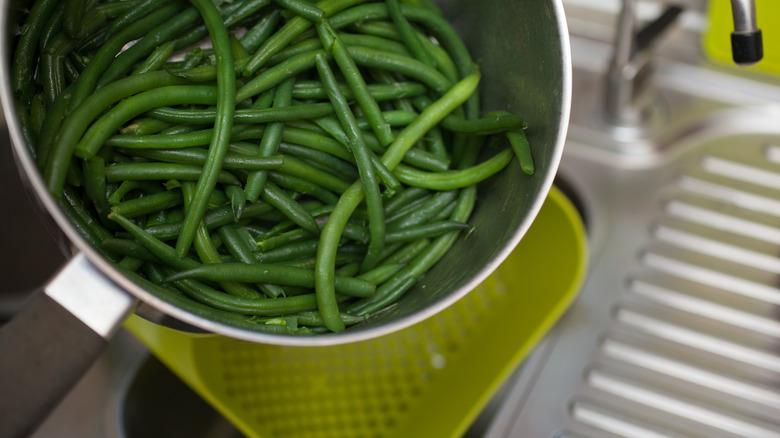 pouring green beans into sieve