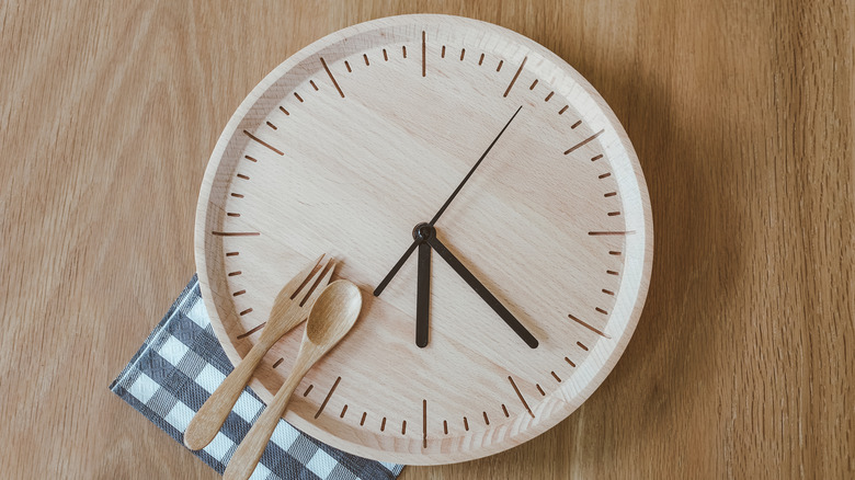 clock design on plate with wooden fork and spoon, navy checked napkin