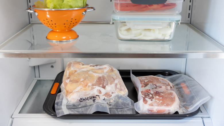 Meat defrosting in fridge on drip tray