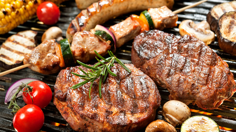 Various meats and veggies cooking on grill