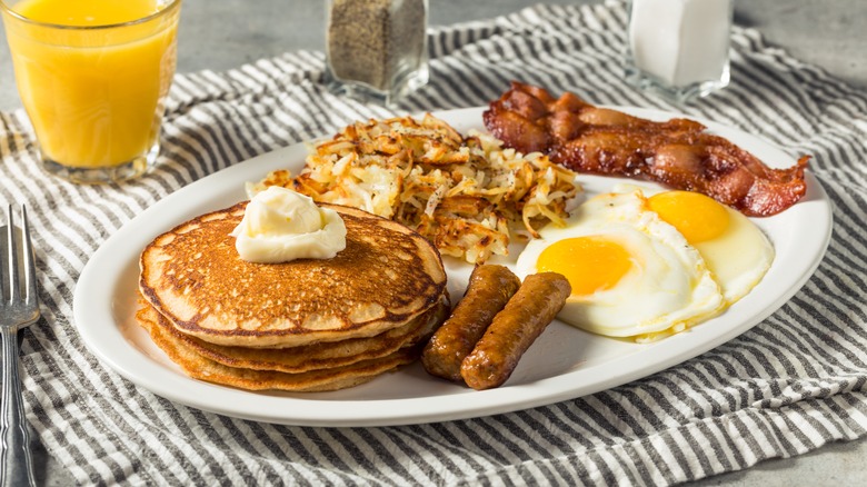 breakfast plate with hash browns, bacon, eggs, and pancakes