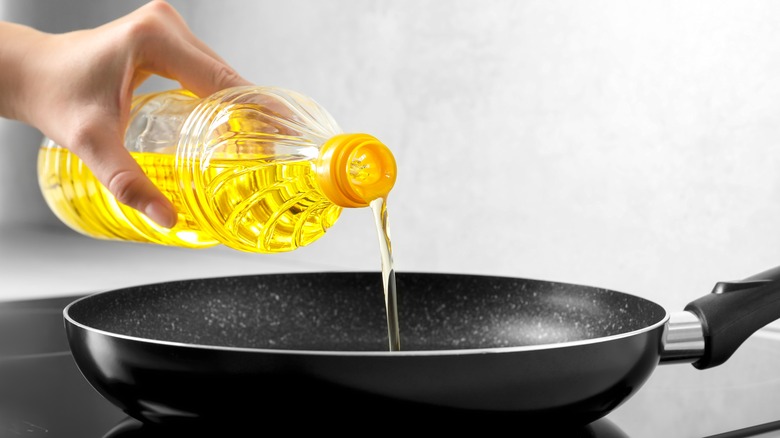 person pouring oil into a frying pan