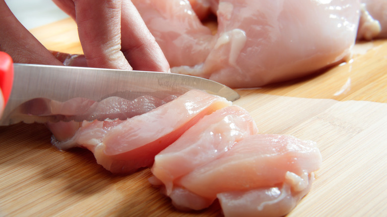 slicing chicken on cutting board