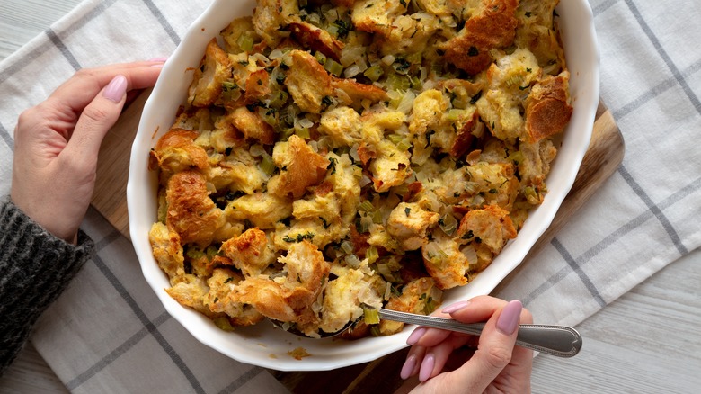 Scooping a spoonful of bread stuffing out of casserole dish