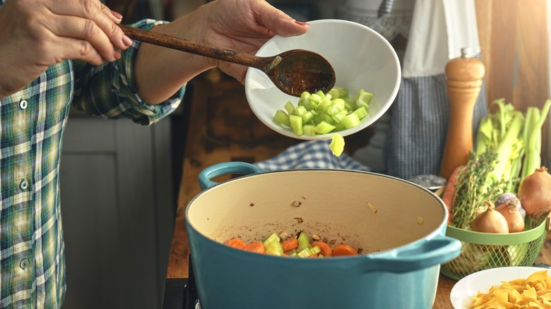 Adding chopped celery to a dutch oven pot