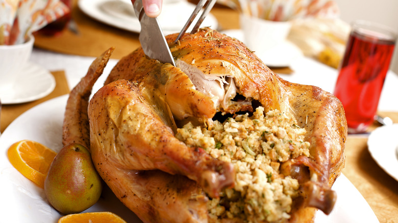 Carving roasted turkey full of bread crumb stuffing