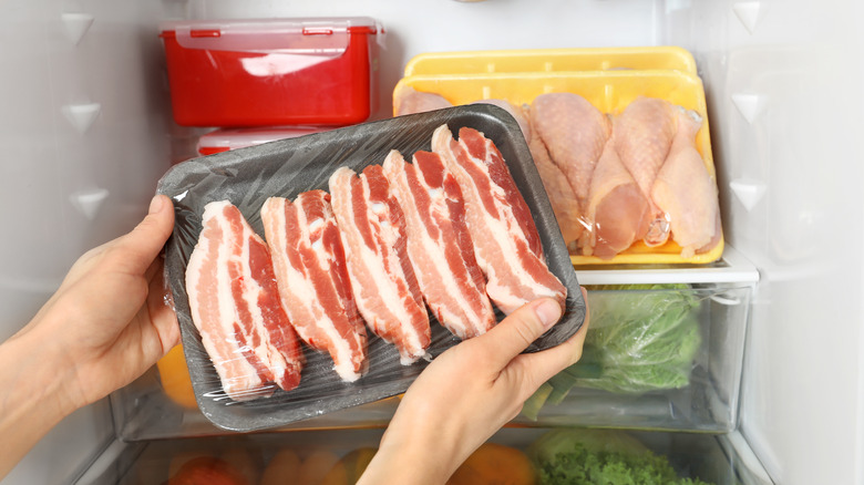 hands removing bacon from fridge