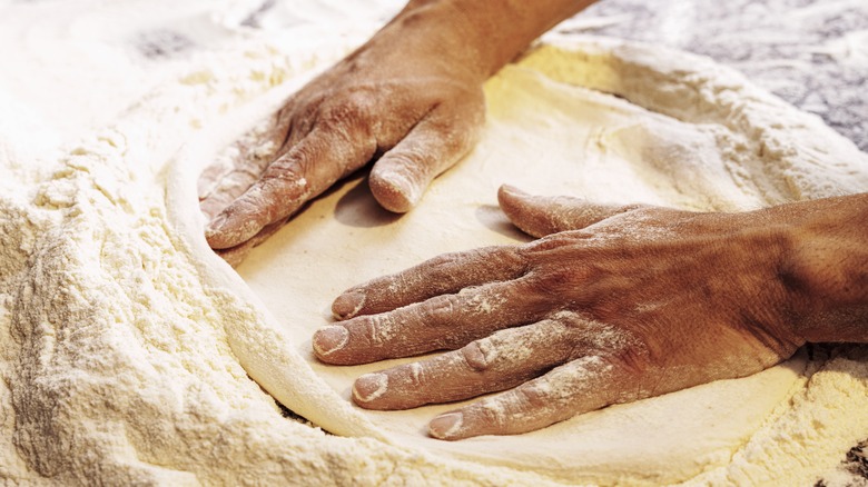 person's hands stretching out dough