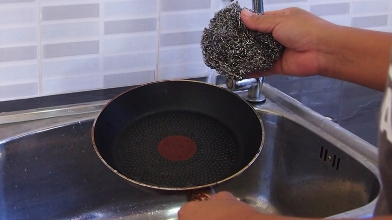 Person using steel wool to clean non-stick pan