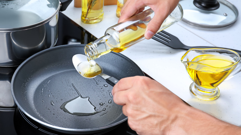 man pouring olive oil in skillet