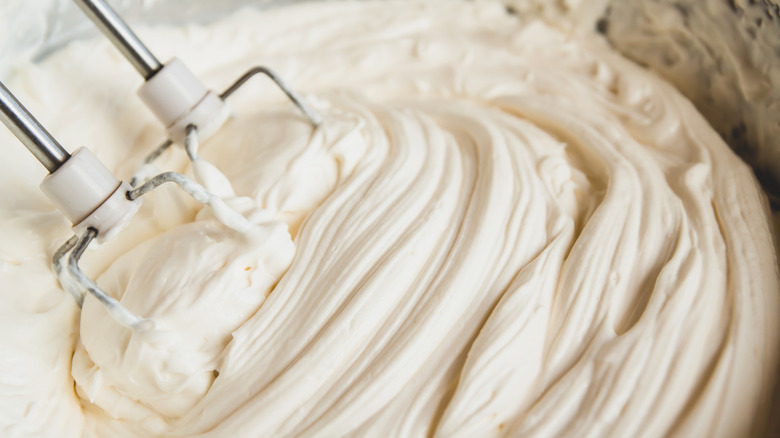vanilla frosting being whipped in metal bowl