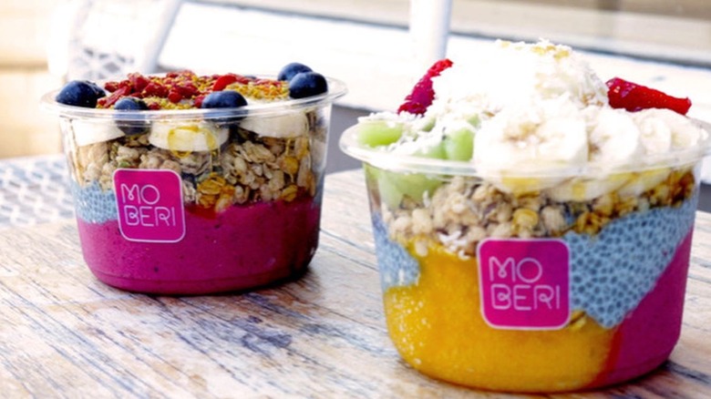 two smoothie bowls topped with granola and fresh fruit